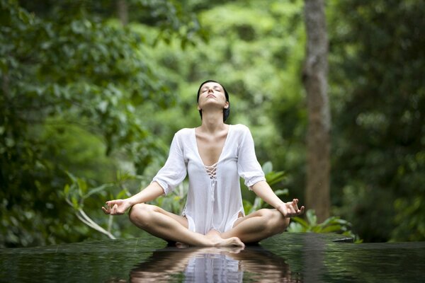 A woman meditates in nature in the lotus position