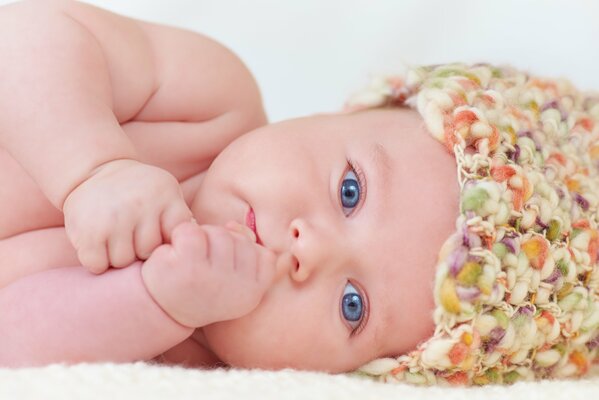 A baby with blue eyes in a colored cap