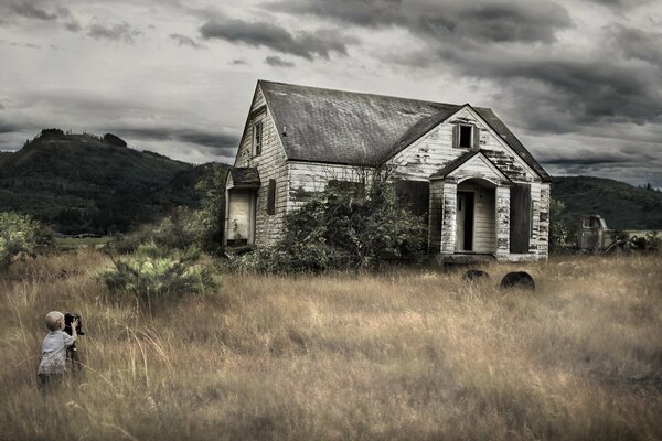 A boy takes pictures of a house on the grass