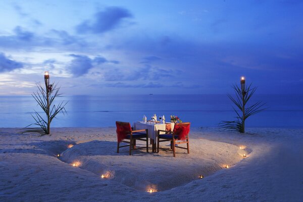 Ein Tisch mit einem romantischen Abendessen am Abend an einem verlassenen Strand