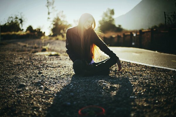 A girl is sitting by the road and the sun is playing in her hair