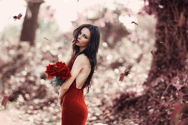A girl in a red dress with a bouquet of red roses