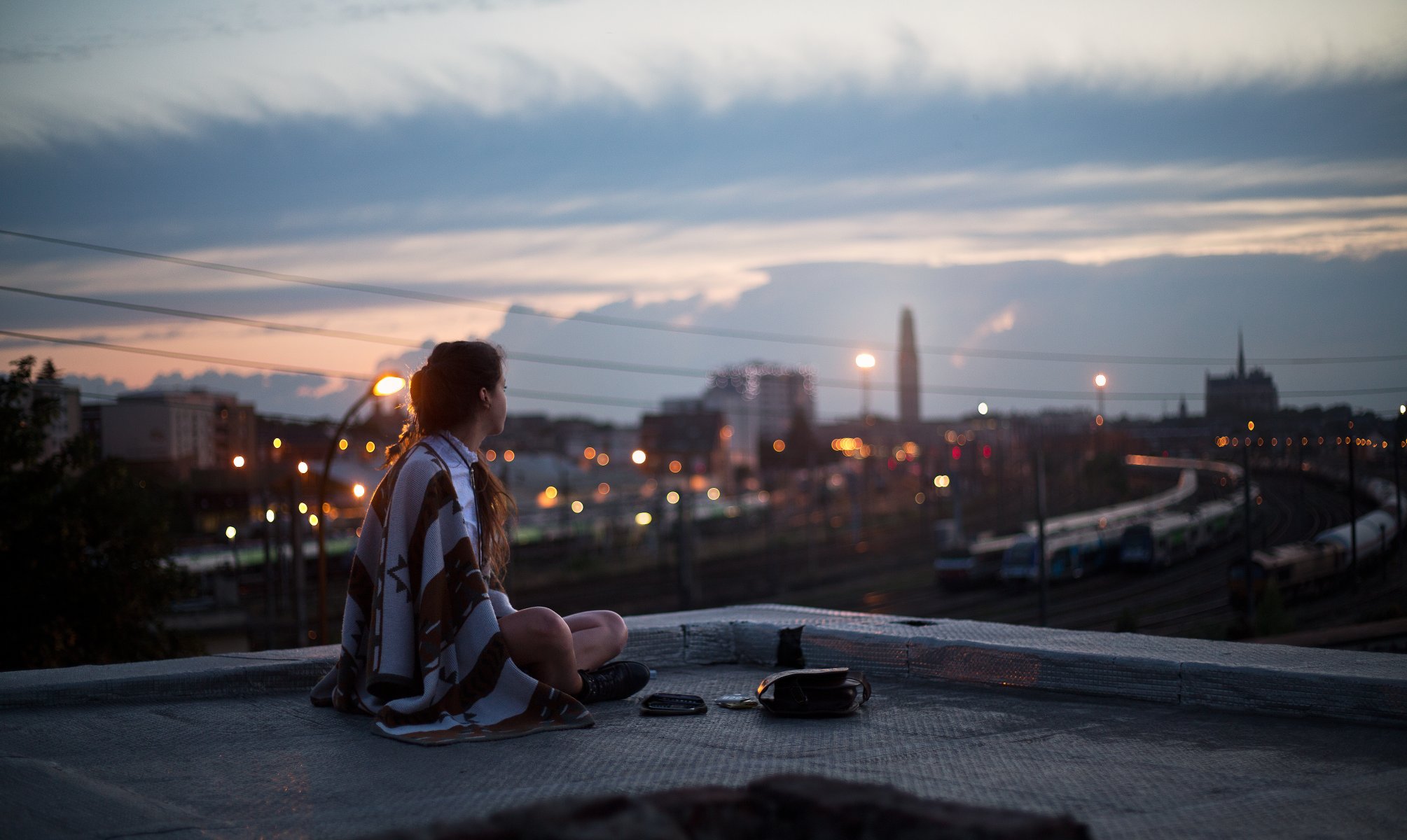 ragazza sera tetto seduta plaid coperta guardando città strada luci lanterne