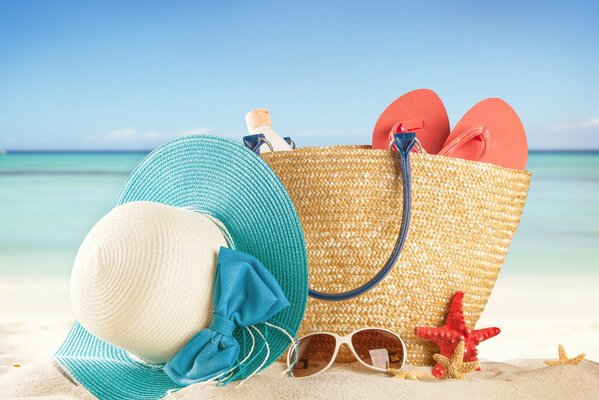 Bolsa de playa y accesorios en la arena junto al mar