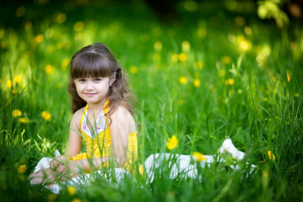 La niña está sentada en la hierba. estado de ánimo de verano