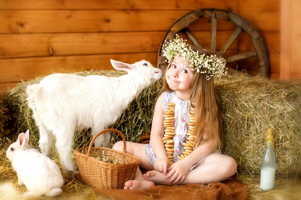 A girl in a wreath feeding a kid and a rabbit