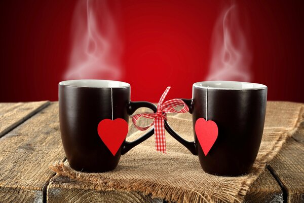 Tazas de corazón negro sobre fondo rústico