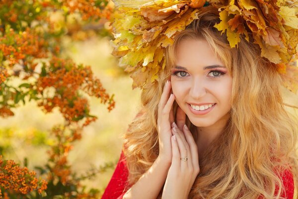 Blonde girl in a wreath of autumn foliage