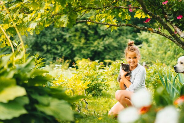 A girl with a cat and a dog in nature