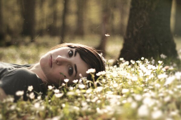 A girl in the forest is lying on flowers