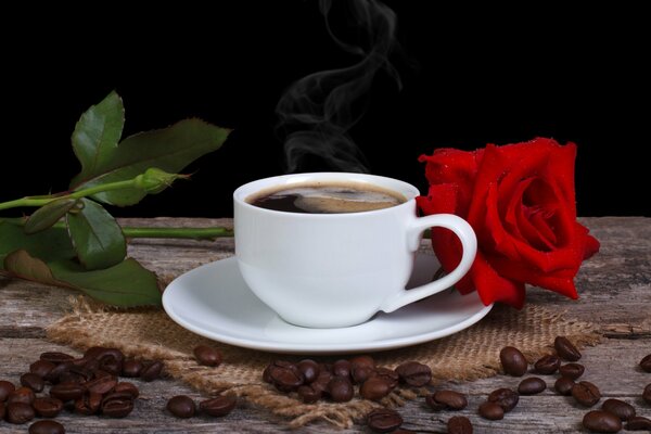 Una taza de café fragante en la mesa con una rosa roja