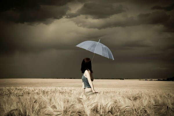 Ragazza con un ombrello sul campo prima di un temporale