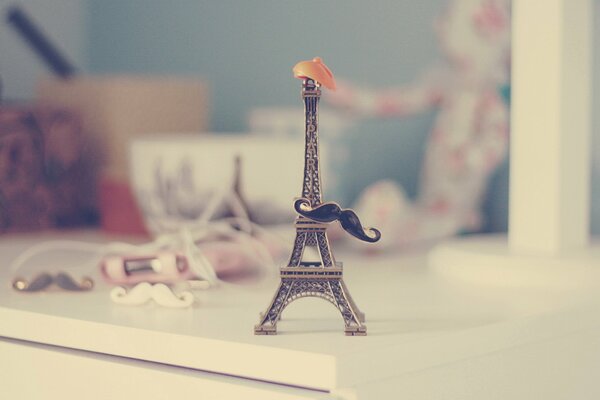 La pequeña torre Eiffel sobre la mesa con sombrero y bigote