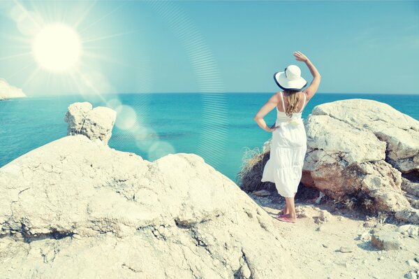 Silhouette of a girl in a white hat on the background of the sea