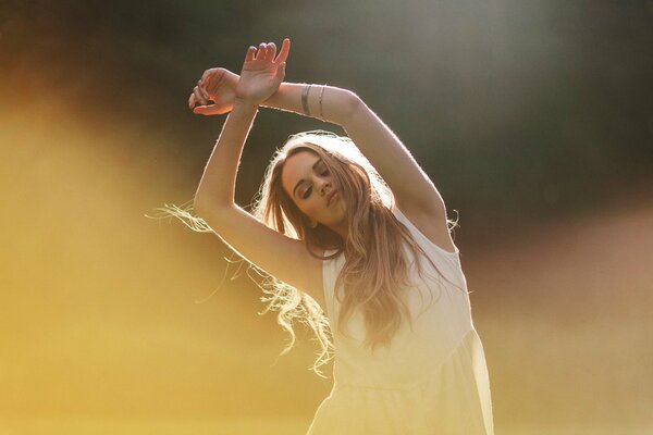 Fille blonde danse avec les mains levées
