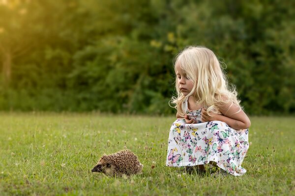 Ein Mädchen sitzt neben einem Igel
