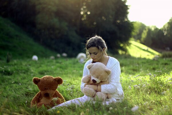 Sad girl sitting with toys in the field