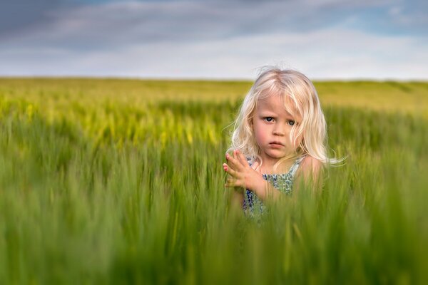 The look of a blonde girl who is sitting on the field