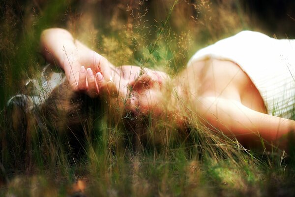 The girl is lying in nature in the grass