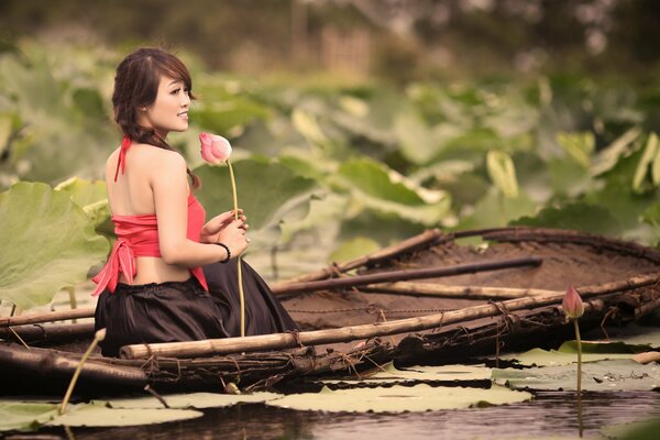 A girl is sailing on a boat and holding a flower