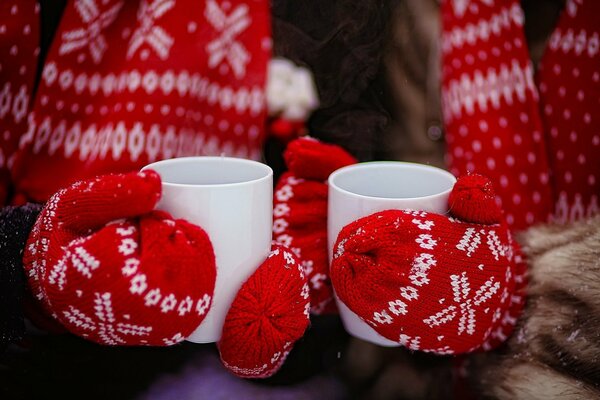 Руки в красных перчатксх держат стакан с чаем