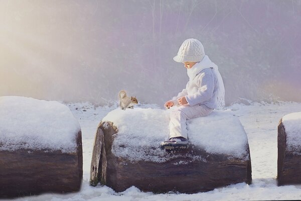 A child feeds a squirrel in winter