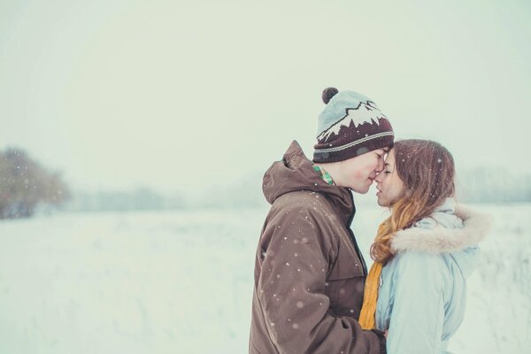 Ragazzo e ragazza si abbracciano dolcemente sullo sfondo della neve