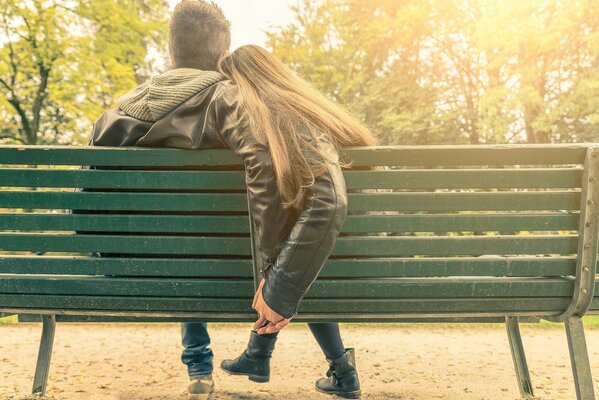Un couple est assis sur un banc vert et le tient par la main