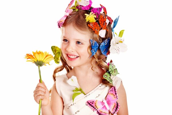 Entzückendes Mädchen mit Schmetterlingen im Haar hält eine Blume