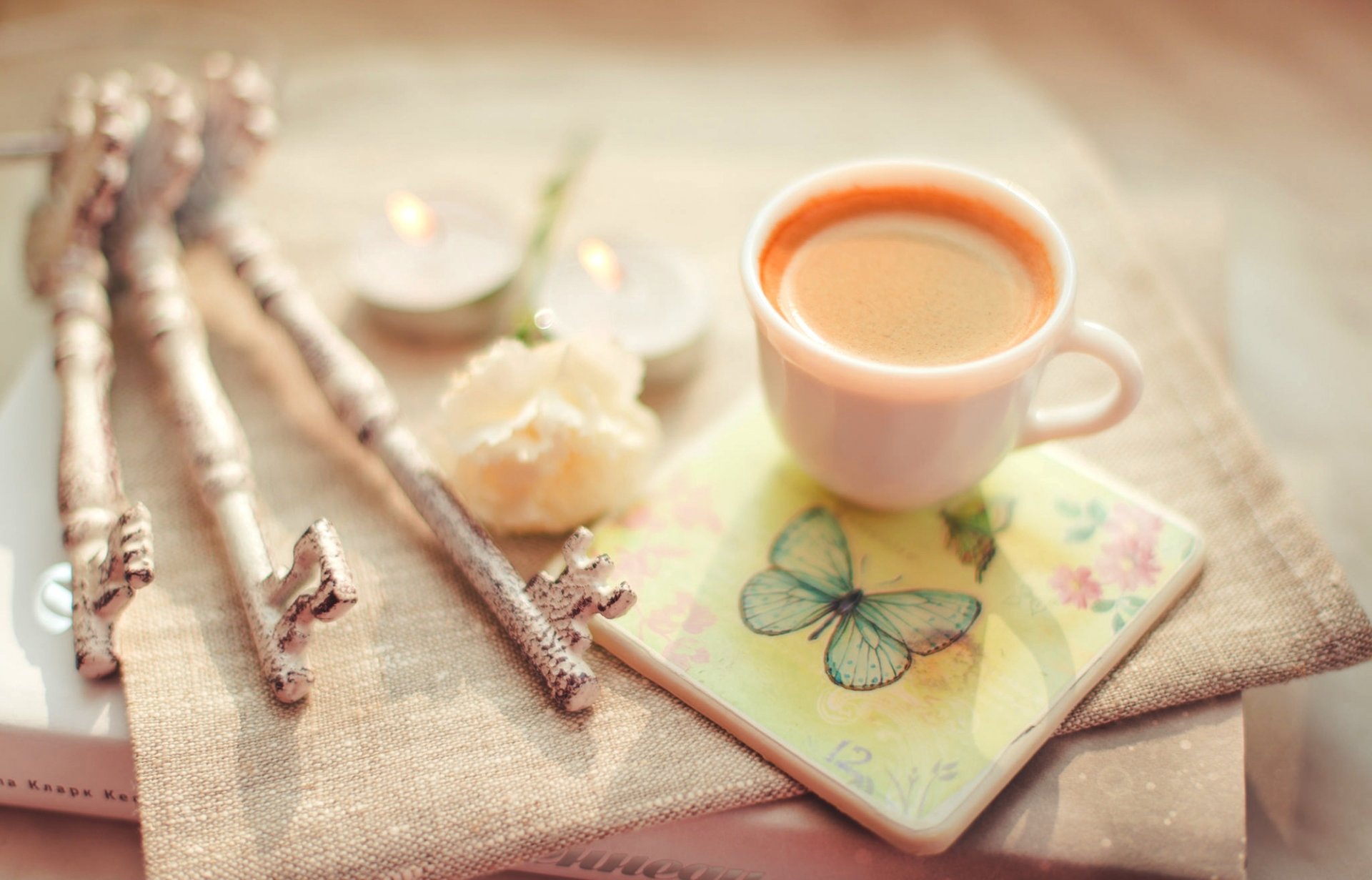 filiżanka kawy cappuccino książka klucze stojak kwiat świece