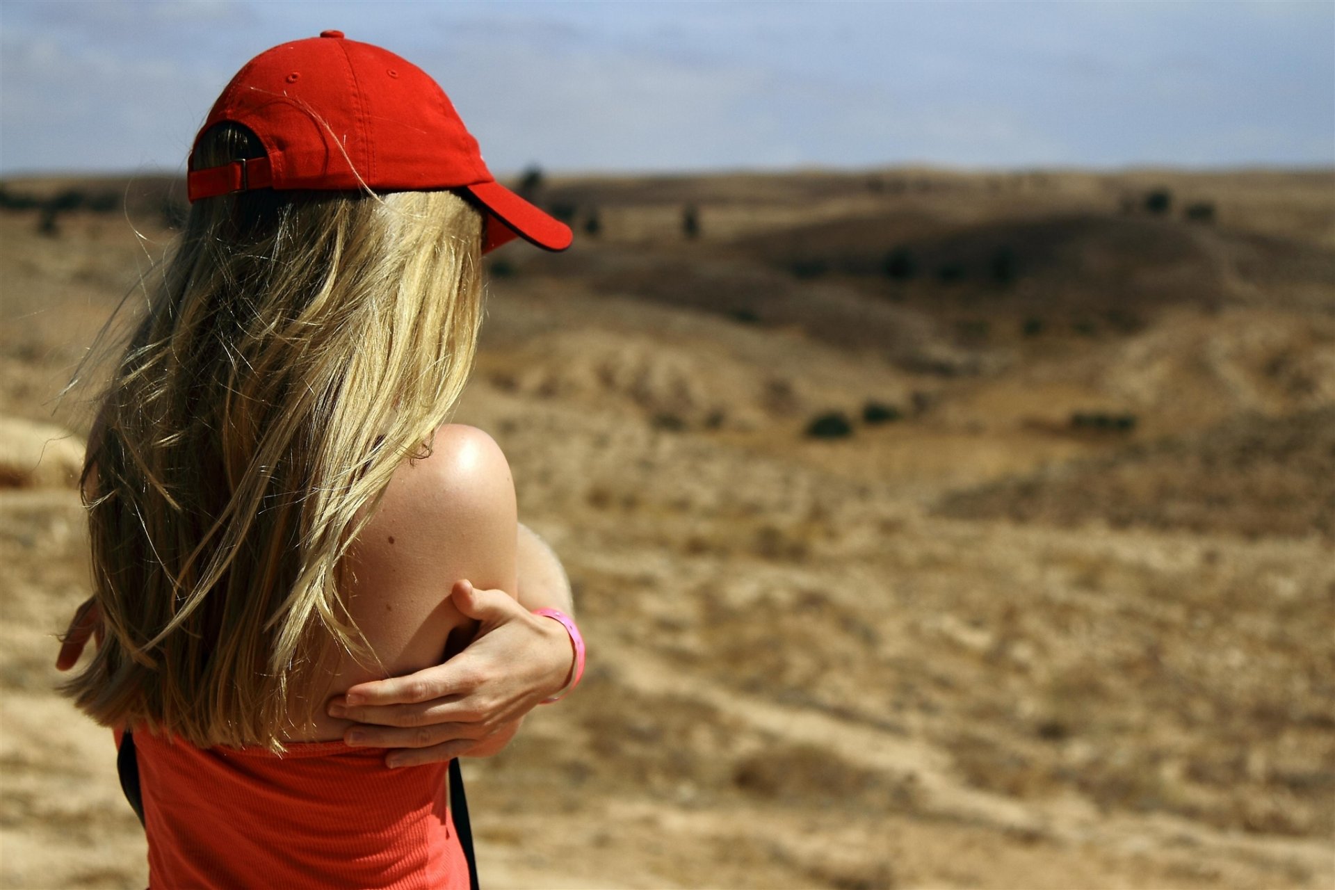 girl blonde red cap jersey shoulders hands the distance hill