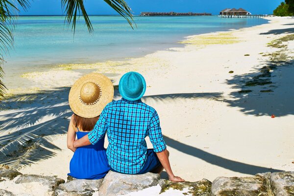 Влюбленная пара в шляпах на пляже