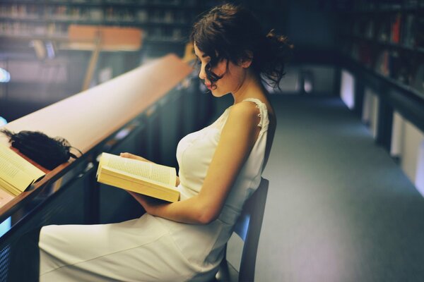 Bella ragazza che legge un libro in biblioteca