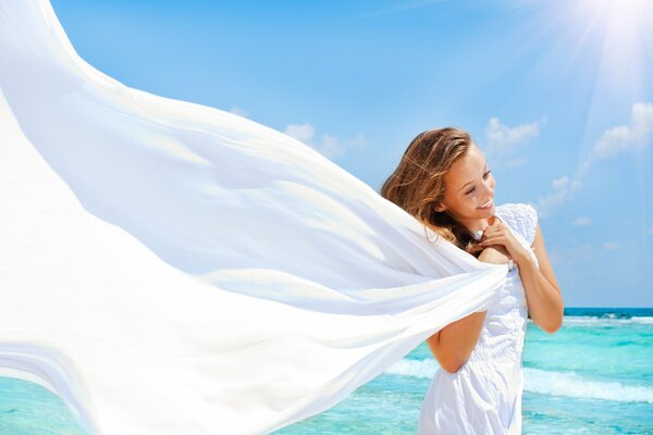 A girl in a white dress with a smile on the background of the sea