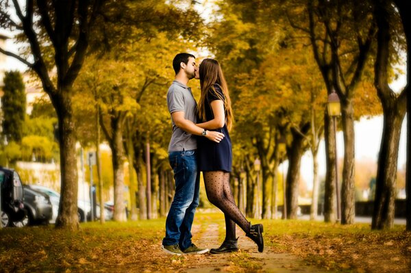 Пара целуется на аллее осенью