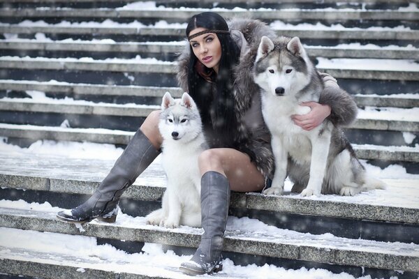 Huskies und Mädchen auf Winterhintergrund