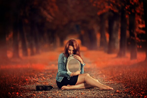 Fille avec un miroir assis le long du sentier d automne