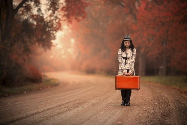Mädchen mit Koffer warten auf den goldenen Herbst