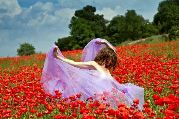 Chica en un vestido volador en el Prado con amapolas