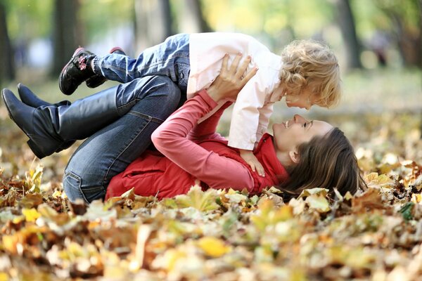 Dziewczyna z dzieckiem bawią się w liściach