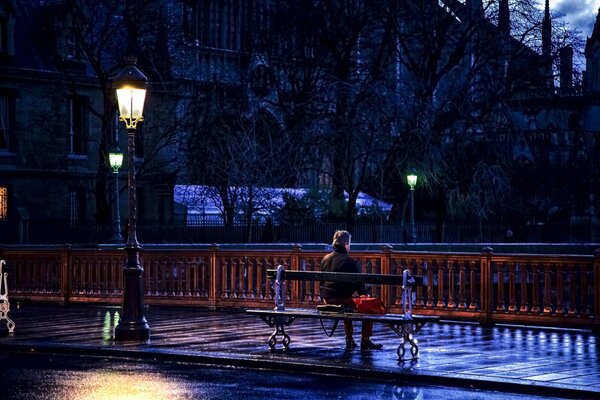 L homme est assis sur un banc sous une lumière à Paris