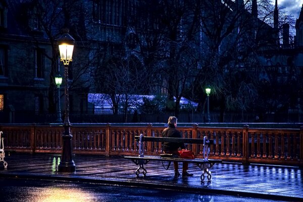 Mężczyzna siedzi na ławce pod latarnią w Paryżu