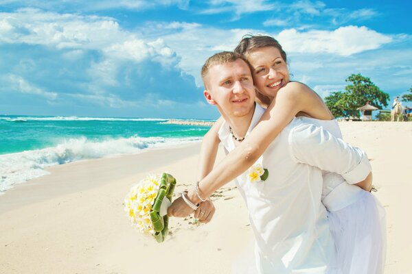 Влюблённая пара на белом песке океана с ромашковым букетом