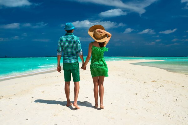 Ai tropici, una coppia passeggia sulla spiaggia tra le palme