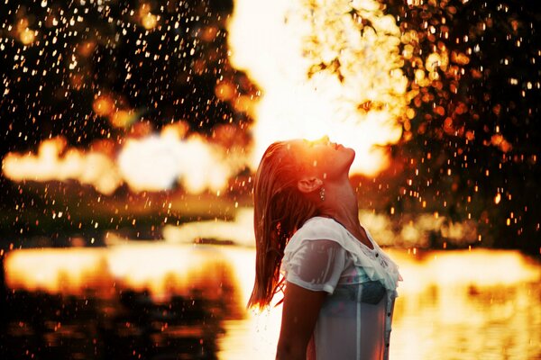 La jeune fille apprécie la pluie au coucher du soleil