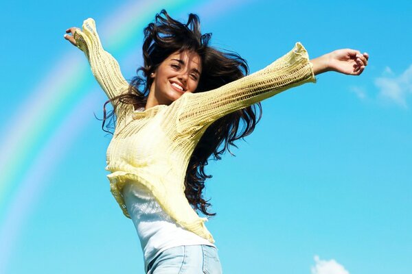 A girl rejoices in a rainbow in the sky