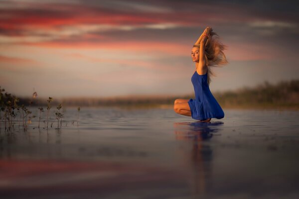 Mädchen im blauen Kleid bei Sonnenuntergang am See