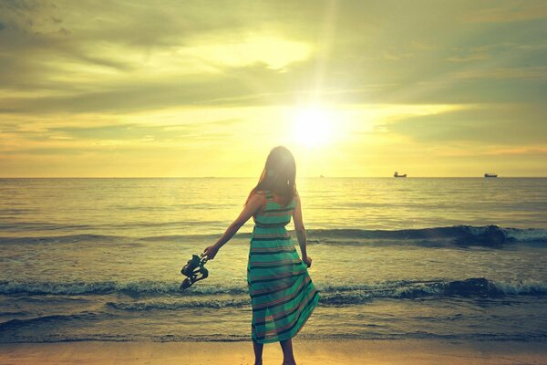 A girl in a dress on the beach against the sunset