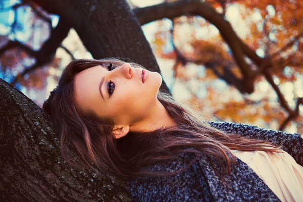 The girl leaned against a tree with a thoughtful look