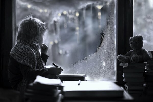 Niño mirando por la ventana de invierno